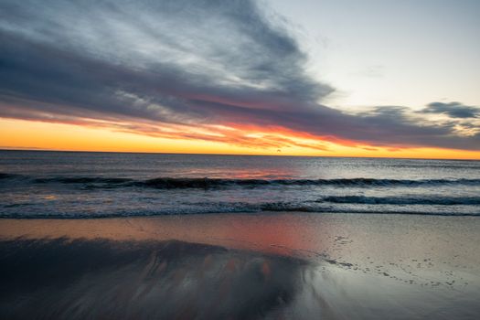 Breathtaking sunset at Orleans Beach, MA with colorful skies and gentle waves.
