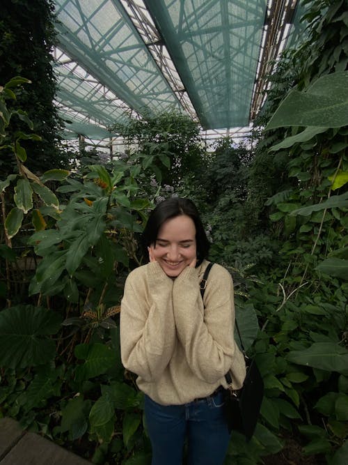 A woman in a sweater standing in a greenhouse