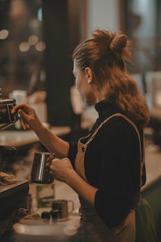 A barista making coffee at a machine, wearing an apron in a warm-lit cafe.