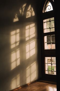 Elegant shadows form on a wall from a classic arched window in warm sunlit tones.
