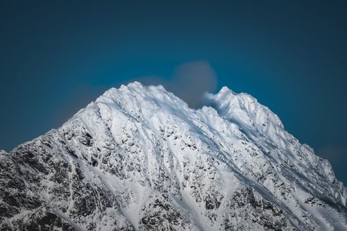 Free A stunning snow-covered mountain peak against a clear blue sky, epitomizing winter's beauty. Stock Photo