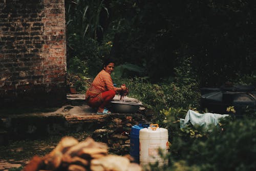 A woman is washing dishes in a small area