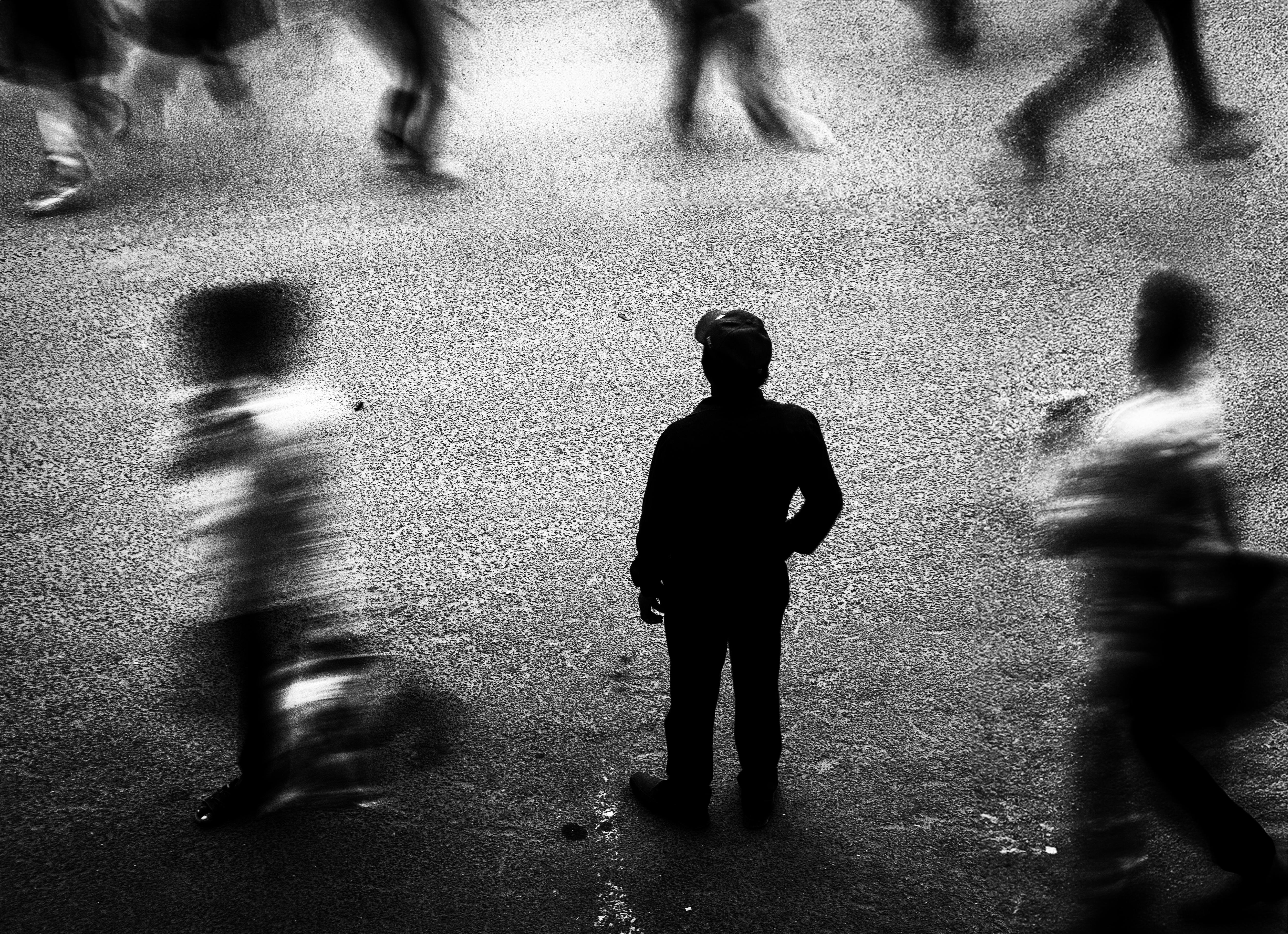 Black and white photo of a lone silhouette in a bustling city street filled with motion blur.