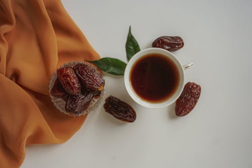 A cup of tea and dates on a white cloth