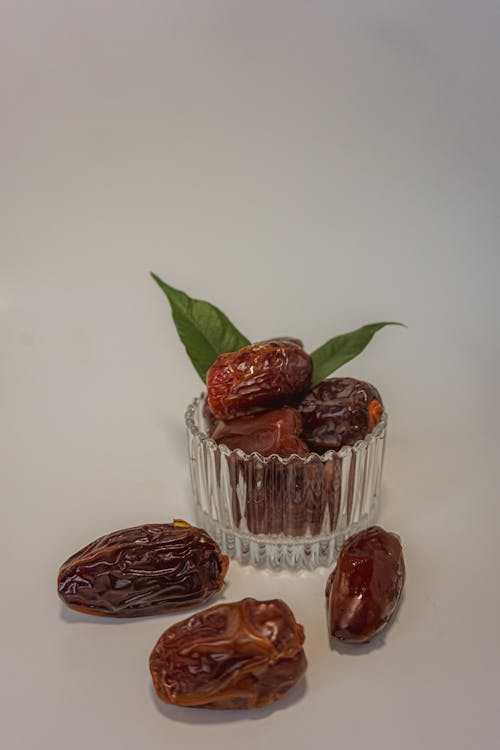 Dates in a glass bowl with leaves on top