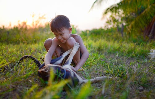 A young boy playing with a snake in the grass