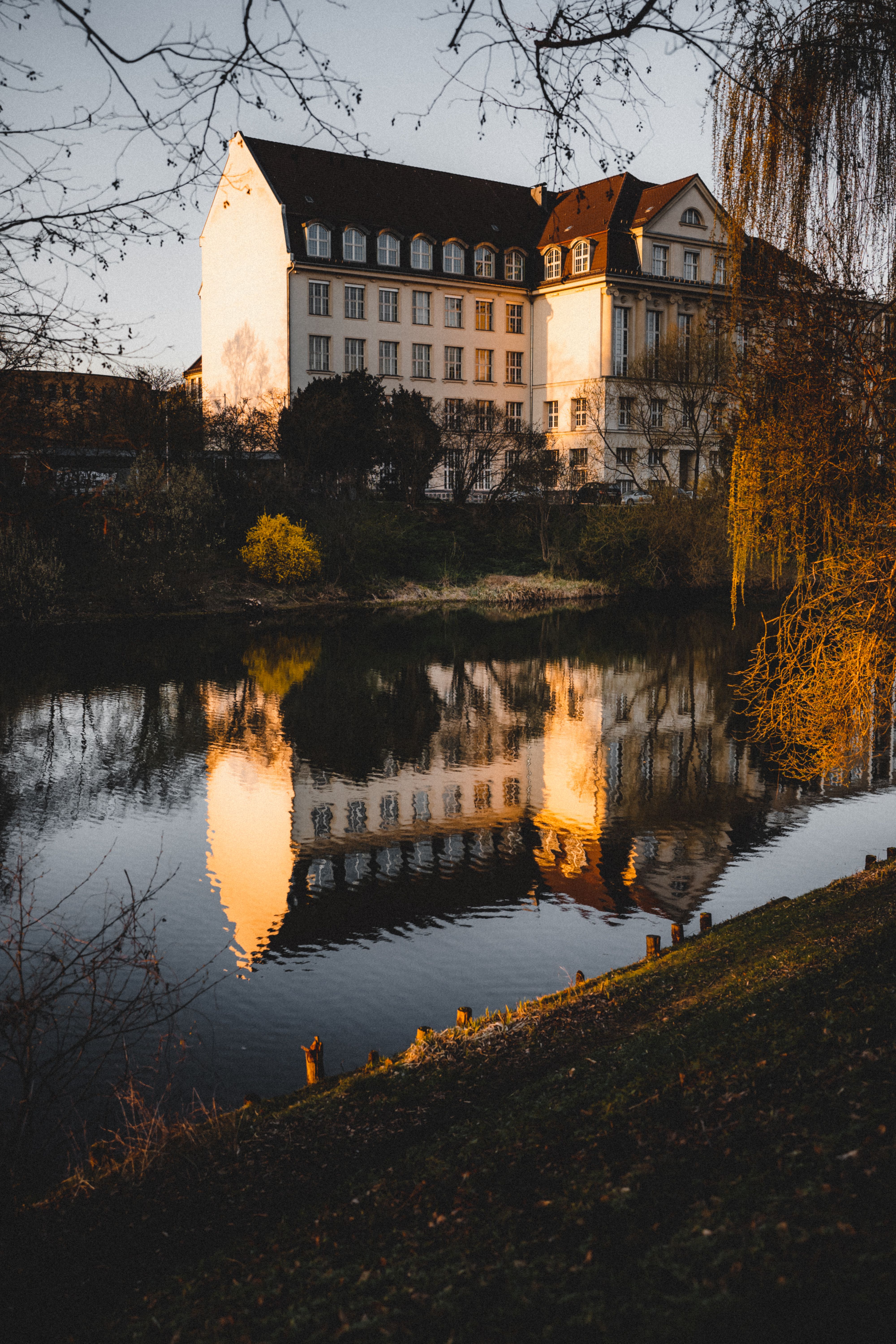 Sunlit reflection of Friedrich-Ebert-Gymnasium on a tranquil river in Berlin, Germany.
