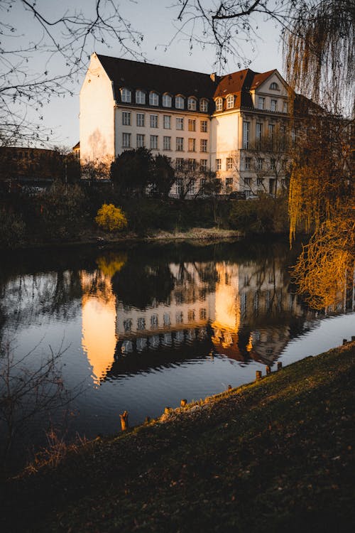 A building is reflected in the water in front of a river