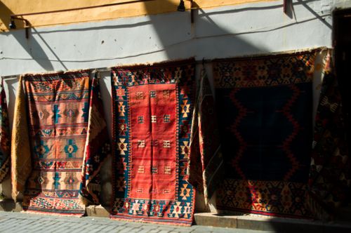 Free Colorful handmade rugs hang along an urban street wall, showcasing traditional patterns. Stock Photo