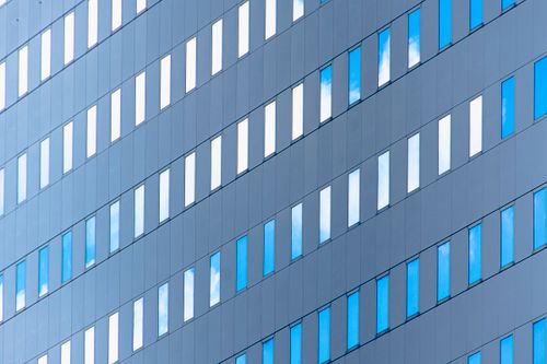 Free Diagonal view of modern office building facade with reflective windows and blue sky reflections. Stock Photo