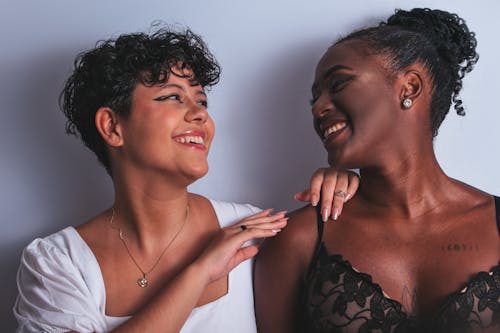 Two women are smiling and one is touching the other's arm