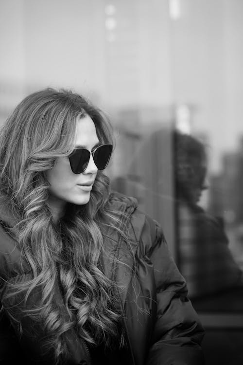 A woman with sunglasses sitting on a window ledge