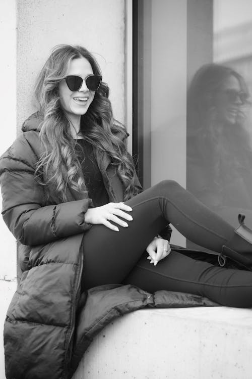 A woman in sunglasses sitting on a ledge