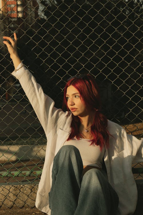 A girl with red hair sitting on the ground