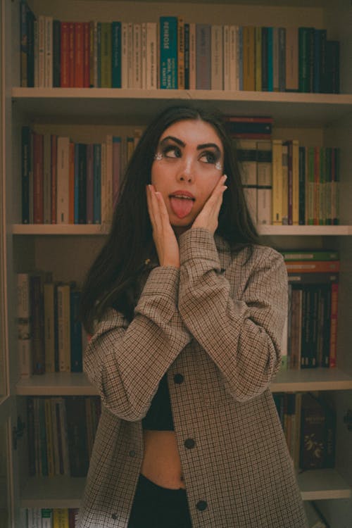 A woman in front of a book shelf with her hands on her face