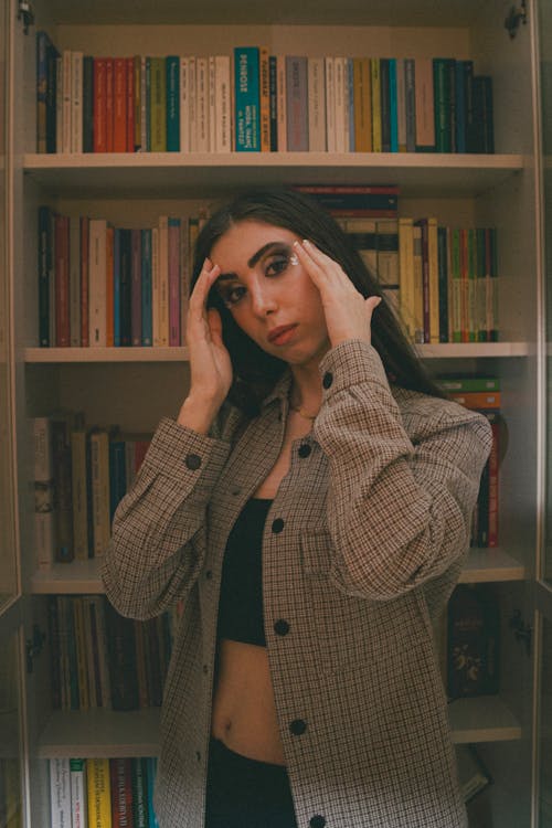 A woman in a jacket standing in front of a bookcase