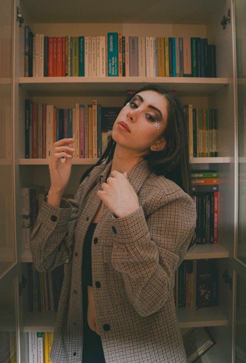 A woman in a jacket standing in front of a bookcase