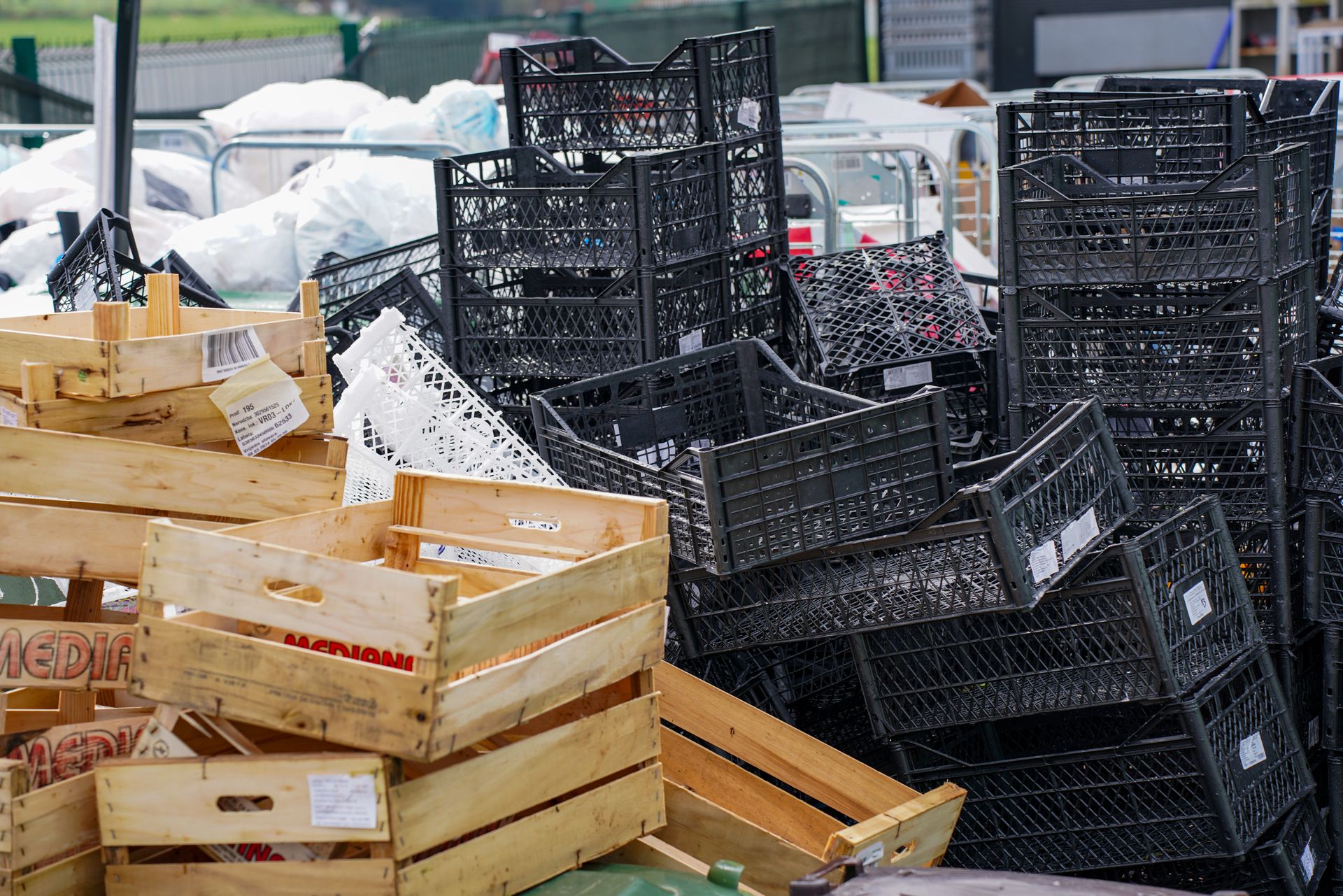 Pile of black plastic and wooden crates in an outdoor market setting.