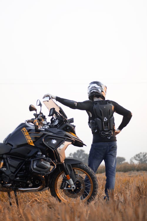 A man standing next to a motorcycle in a field