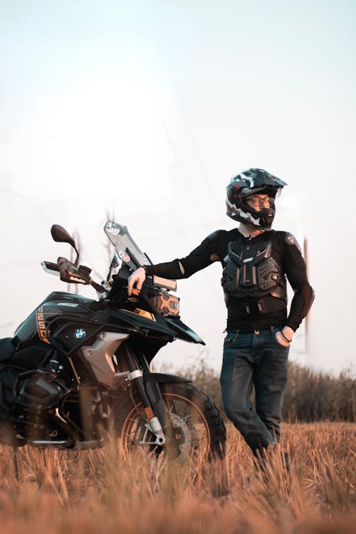 A man standing next to his motorcycle in a field