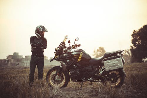 A man standing next to his motorcycle in a field