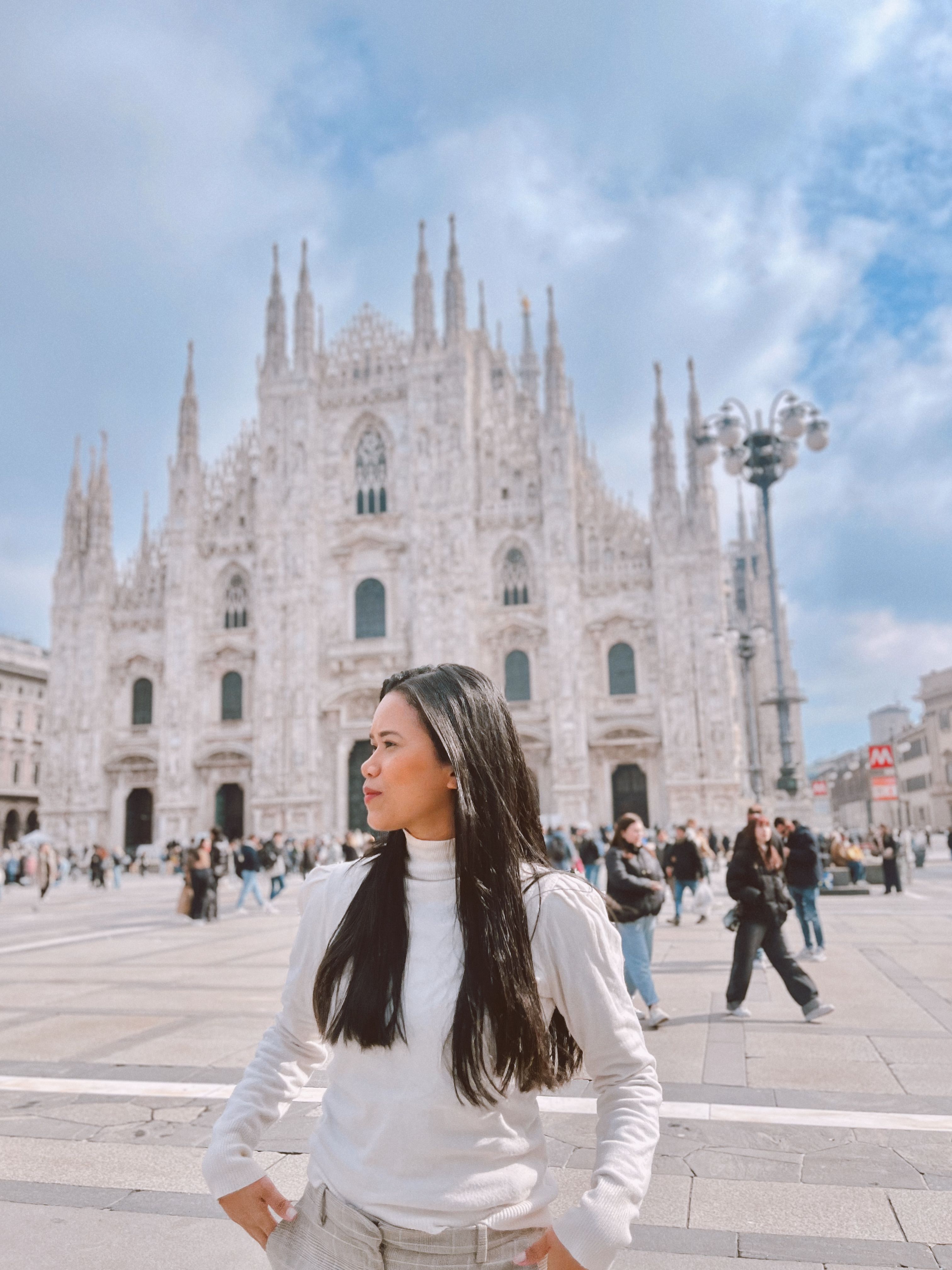 Stylish woman standing in front of the iconic Milan Cathedral on a sunny day.