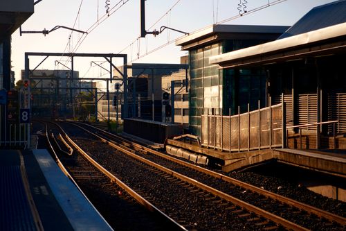Free Sunset view of an empty urban railway station with tracks curving into the distance. Stock Photo