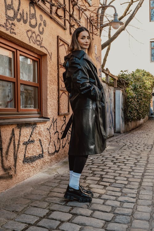 A woman in a black leather coat and white sneakers