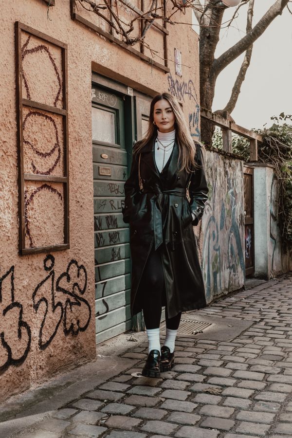 Woman in black trench coat with white turtleneck and black leggings