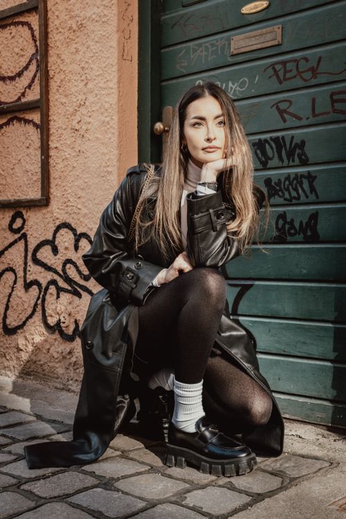 Free Fashionable woman in leather coat posing against graffiti wall on an urban street. Stock Photo