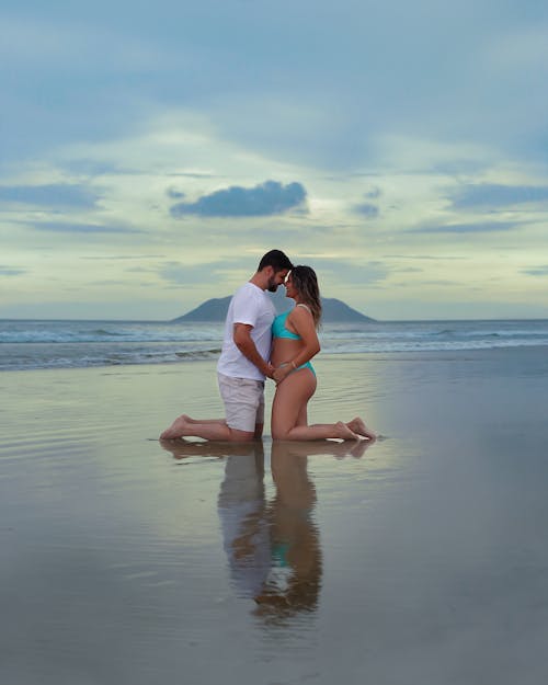 A couple kissing on the beach in front of the ocean