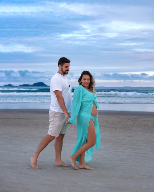 A pregnant woman and her husband walking on the beach