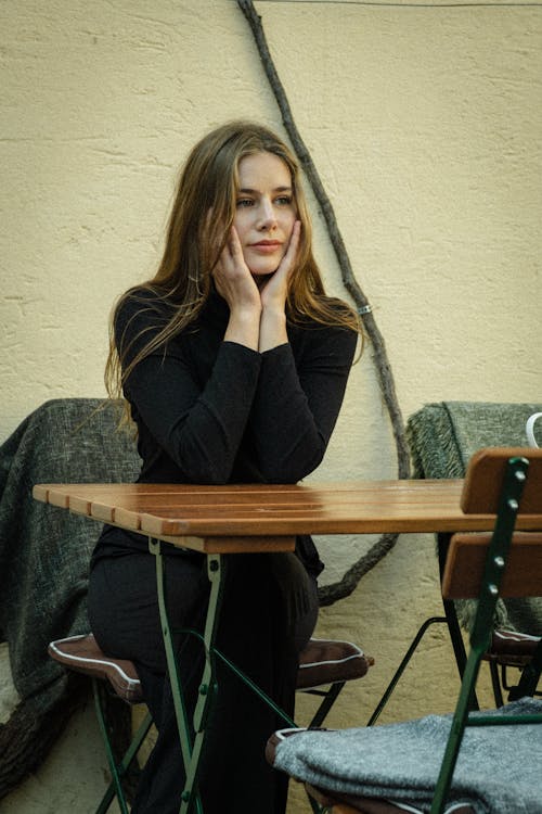 A woman sitting at a table with her hands on her lap