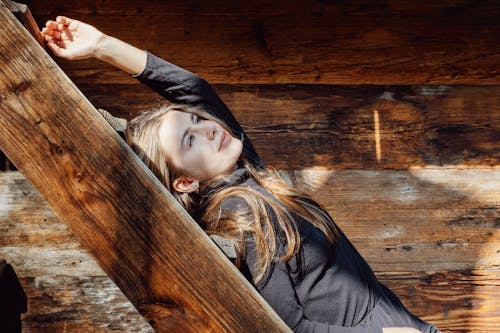 A young woman laying on a wooden beam