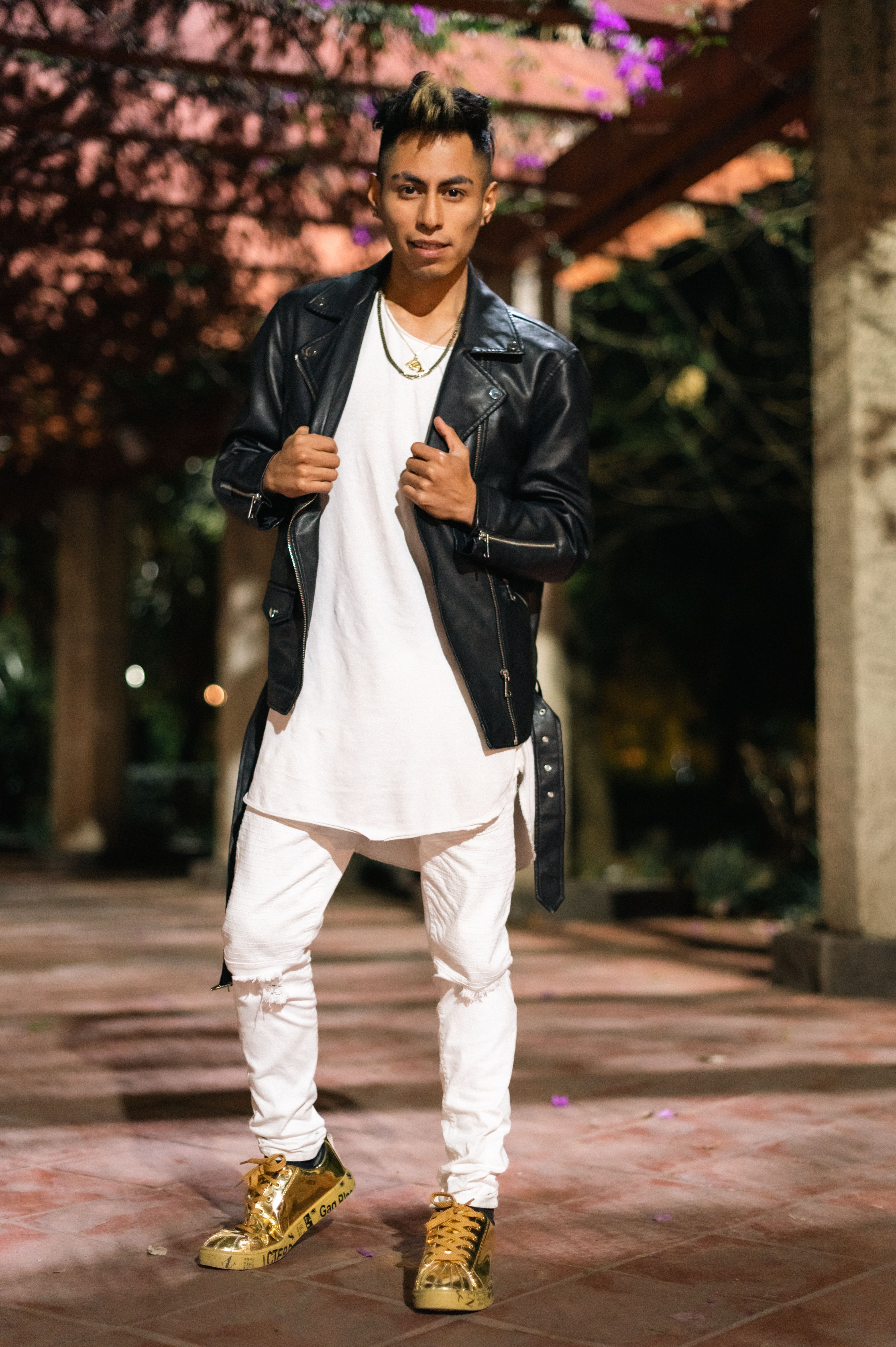 Young male model in stylish attire posing in urban setting, night shot.