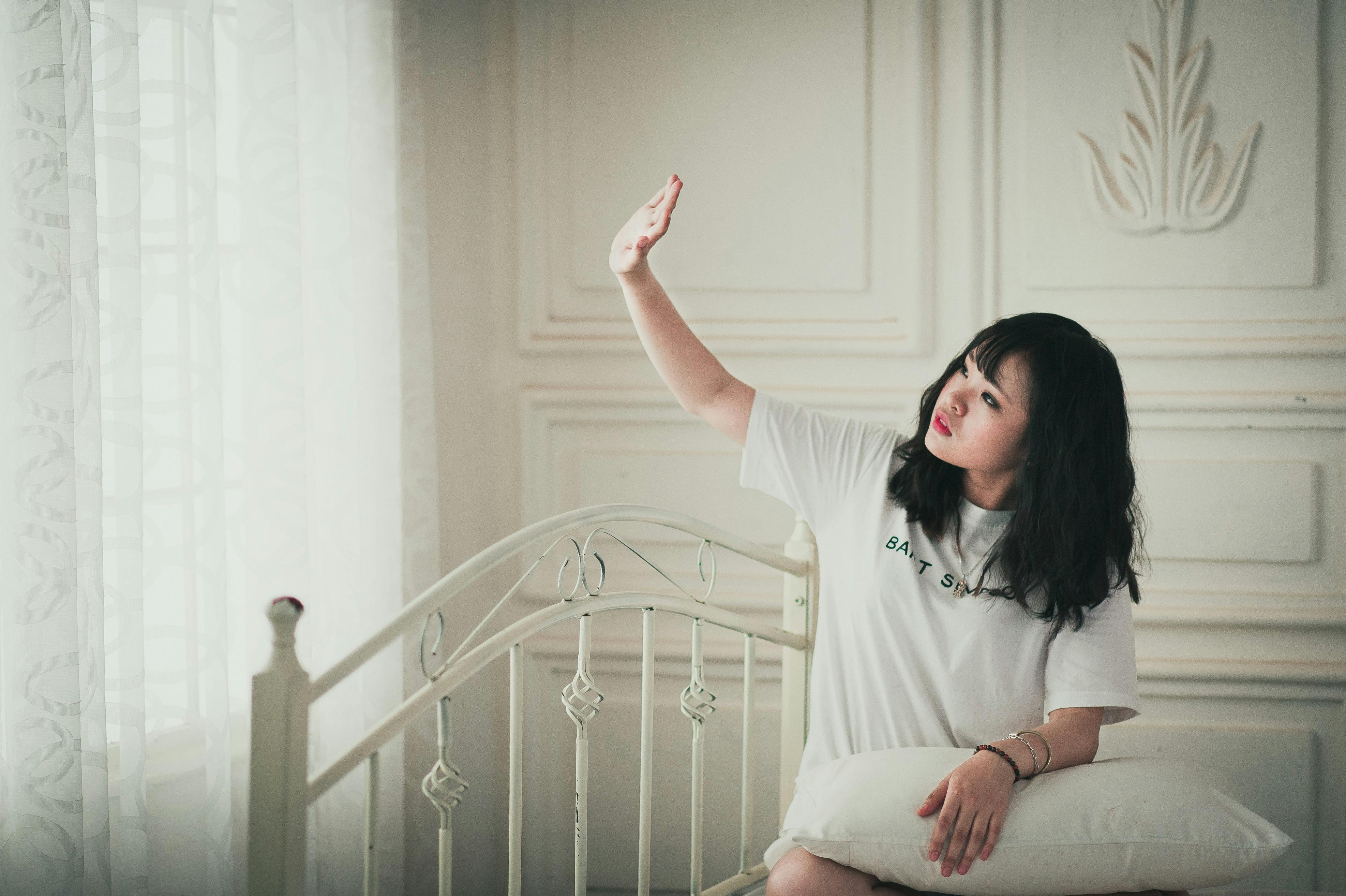 在舒适的卧室里，女人享受着阳光，表达出放松与和平