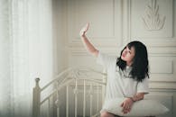 在舒适的卧室里，女人享受着阳光，表达出放松与和平