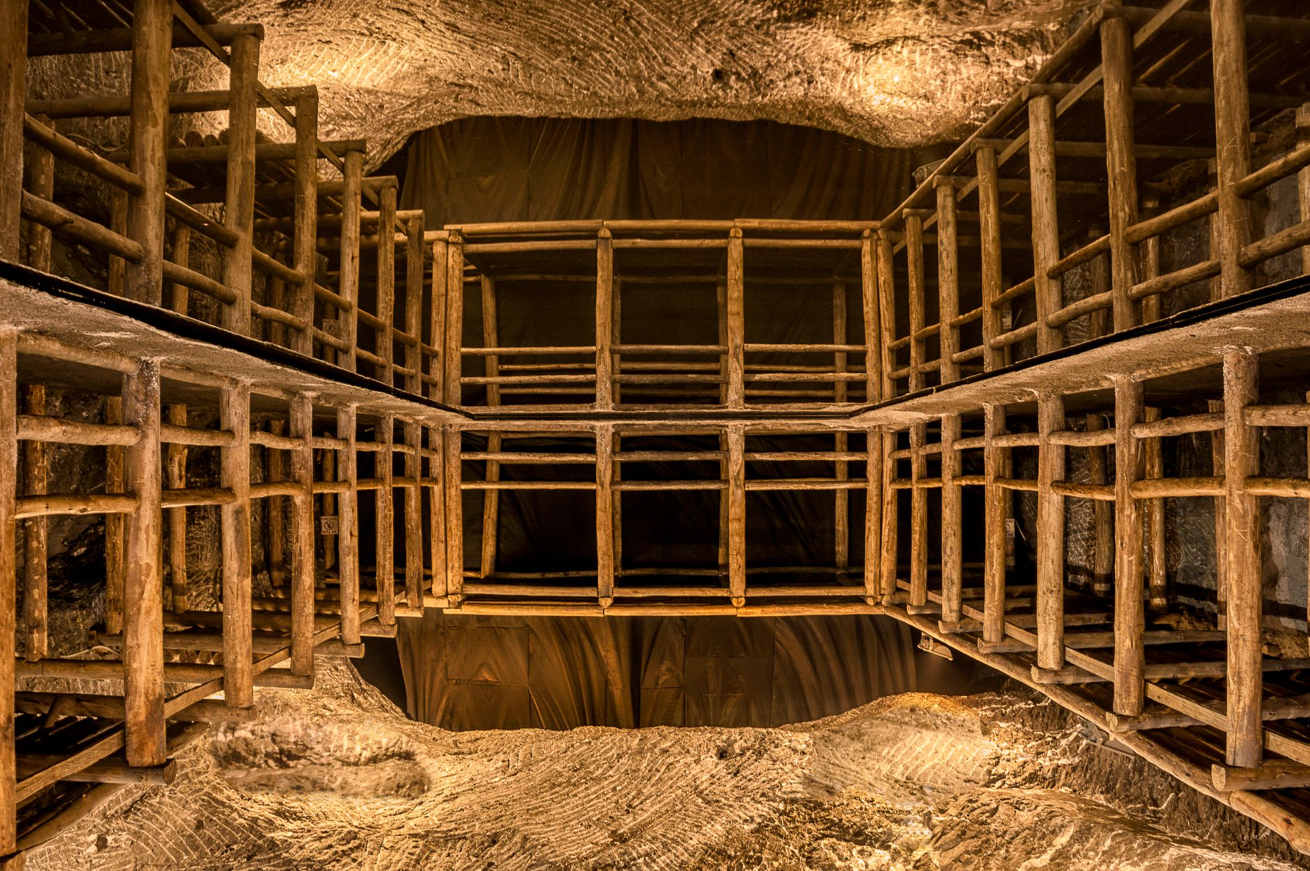 Intricate wooden scaffolding structure inside a well-lit underground cave or mine shaft.