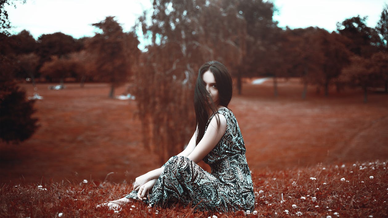 Woman in Black and Gray Dress Sitting on Grass Field
