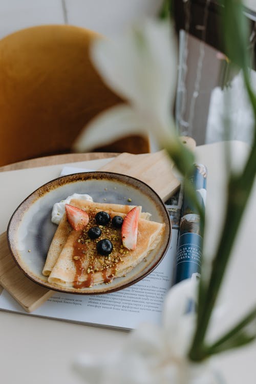 A plate with a crepe and a flower on it