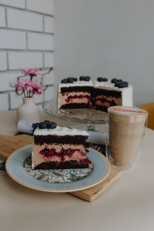 A slice of cake with berries and coffee on a plate