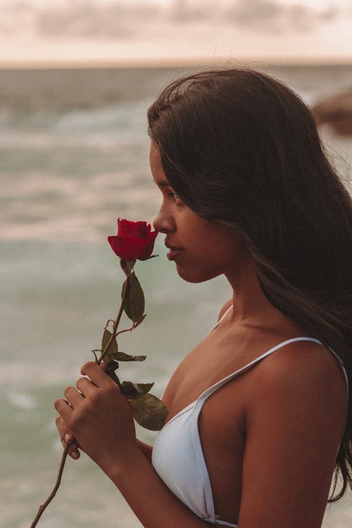 A woman in a white bikini holding a rose
