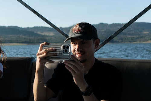Man in Cap Sailing and Taking Pictures with Smartphone