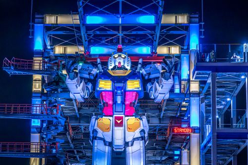 Free Illuminated Gundam robot at Yokohama's Gundam Factory lit up at night. Vibrant colors and futuristic design. Stock Photo