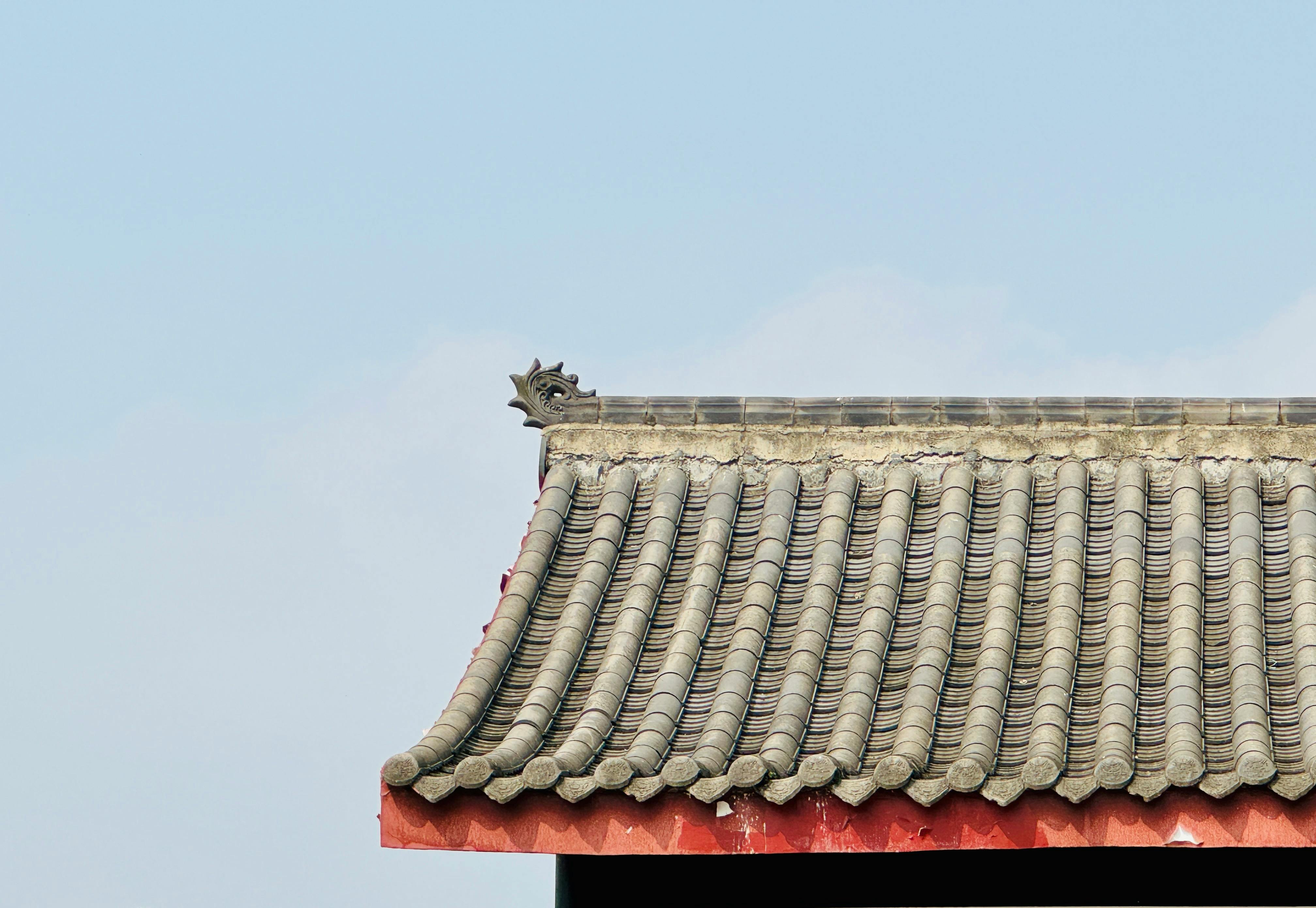 Close-up of a traditional Asian temple rooftop showcasing intricate tile patterns and dragon ornamentation against a clear sky.