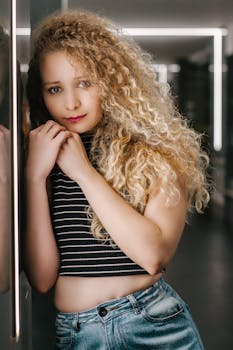 一位女性身着休闲装，在柔和的灯光下于室内摆出姿势，营造出现代氛围