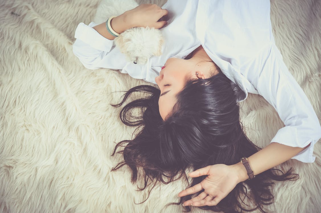 Woman Lying on Beige Faux-fur Mat resting