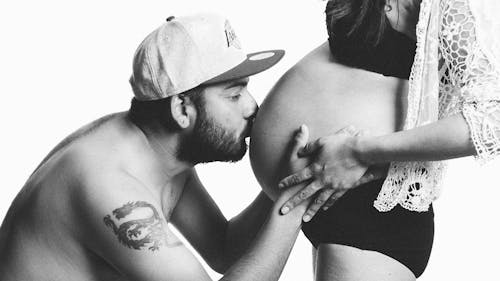 Grayscale Photography of Man Kissing Woman's Pregnant Bell