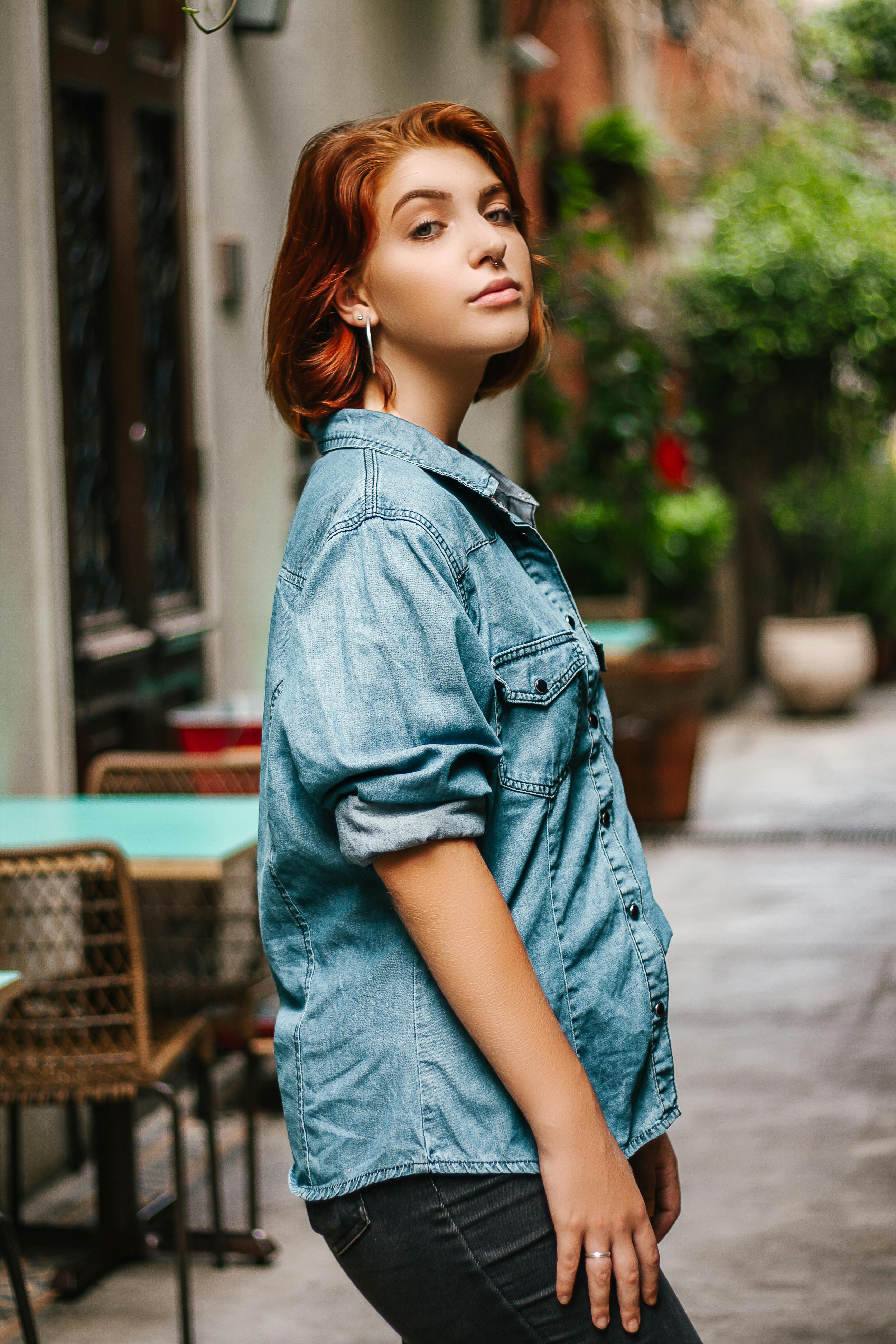 Pretty stylish woman in denim shirt and jeans posing outdoors against  orange wall background. Stock Photo | Adobe Stock
