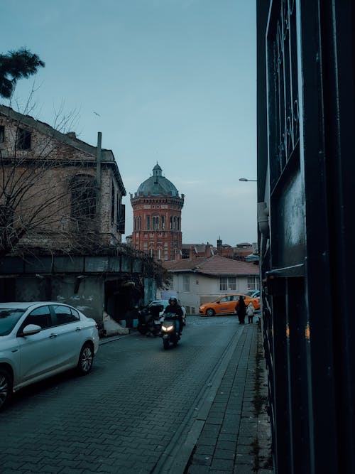 A car is driving down a street with a clock tower in the background